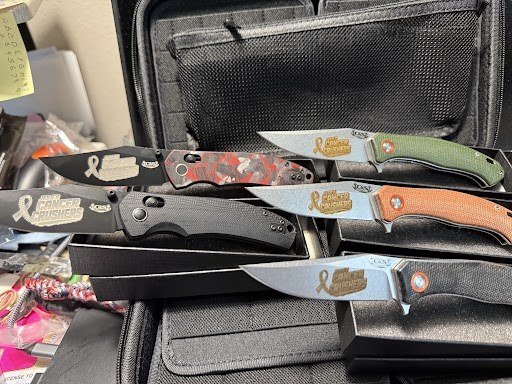 Five folding knives with custom Cancer Crushers ribbon engravings on the blades, laser engraved by C&S Knifes