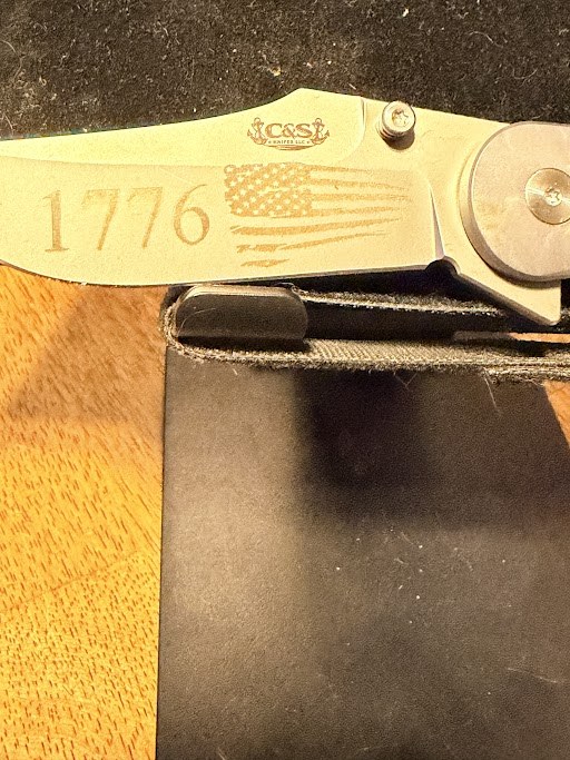 Folding knife blade engraved with 1776, a tattered American flag, and the C&S Knifes logo