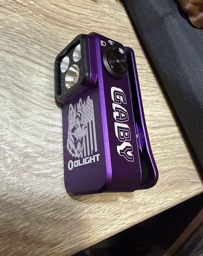 Purple Olight Oclip engraved with a German Shepherd and American flag on the face and the name GABY down the side