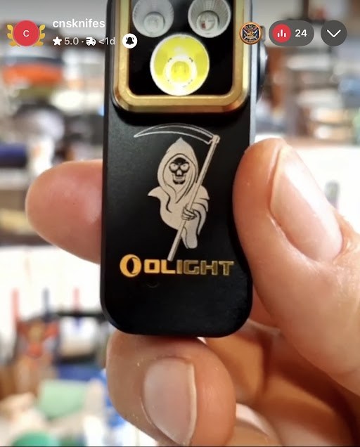Olight flashlight with a grim reaper image laser engraved on the black aluminum body
