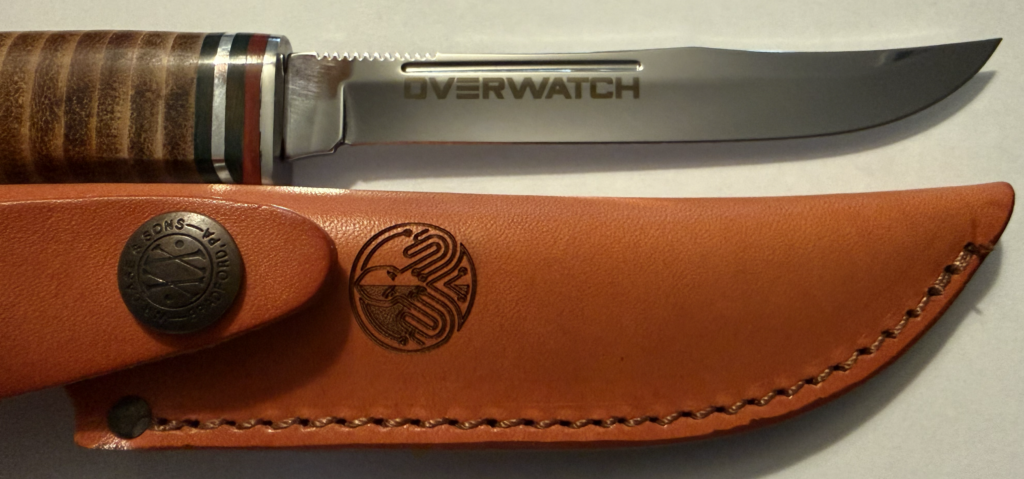 Fixed-blade knife with a stacked leather handle beside its tan leather sheath, OVERWATCH engraved along the blade.